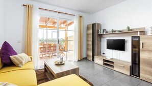 Una sala de estar moderna con un sofá amarillo, una mesa de centro y un televisor de pantalla plana montado en un mueble de madera.