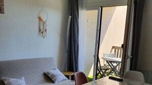 Una sala de estar moderna con un sofá, una mesa de comedor con cubierta de vidrio y vista a un patio al aire libre.