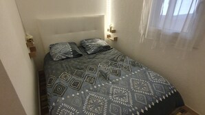 Una cama con ropa de cama estampada en una habitación con suelo de madera y pared blanca.