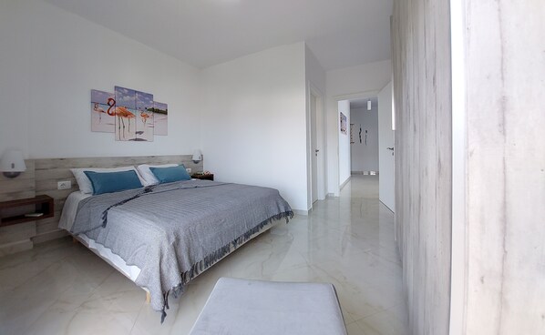 A bedroom with a bed, nightstands, a wall-mounted lamp, and a painting. - CIRASOLA HOME (Saranda)