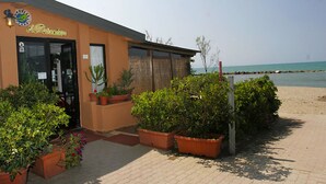 A building with a sign reading "La Perla" and potted plants in front. - Apartment La Ginestra directly on the beach (Albinia)