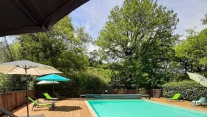 A wooden deck with a swimming pool, surrounded by trees and equipped with sun umbrellas and lounge chairs. - Village of 10 lodgings with heated outdoor swimming pool, restaurant on 1 hectare (Calviac en Périgord)