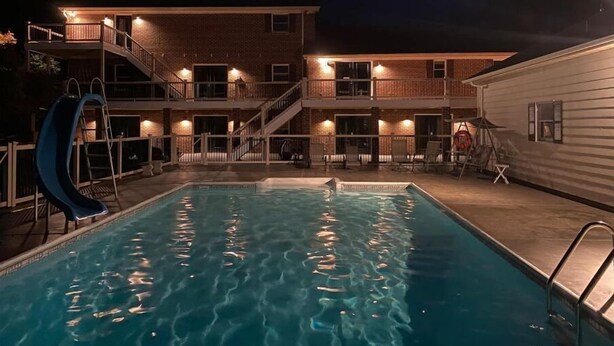 A multi-story building with a swimming pool, outdoor seating, and a slide.