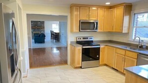 A modern kitchen with wooden cabinets, a stainless steel refrigerator, a microwave, and an oven.