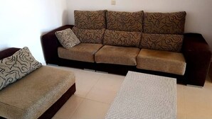 A living room with a brown sofa, a patterned throw pillow, and a small table. - Casa Do Castillo (Fisterra)