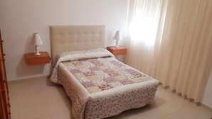 A bedroom with a bed, two bedside tables with lamps, and a window with curtains. - Casa Do Castillo (Fisterra)