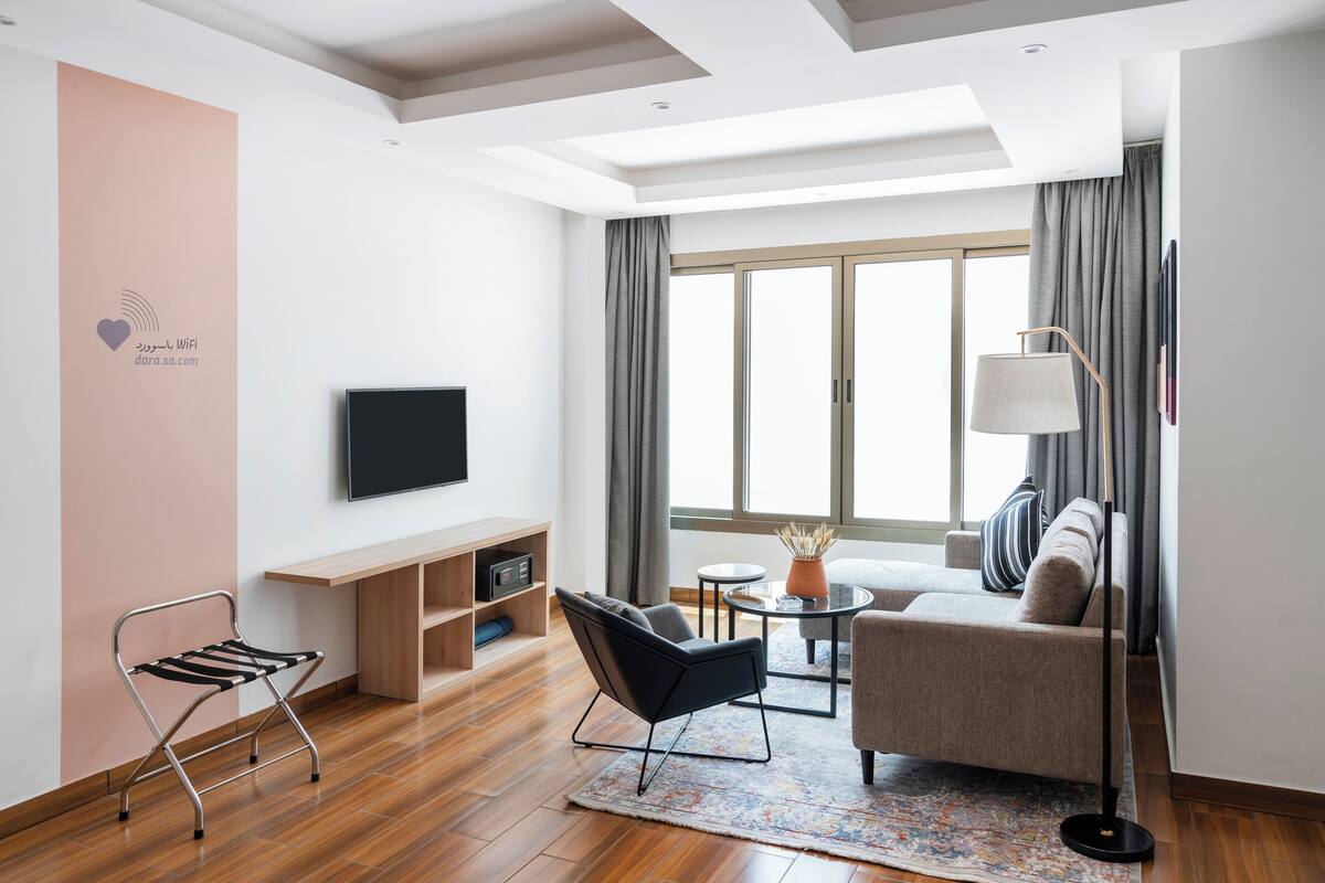 A modern living room with a sofa, a coffee table, a TV, and a lamp.