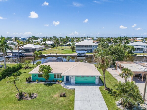 A residential area with houses, a swimming pool, and a clear blue sky. - Waterfront 3BR, Gorgeous Pool, Bed Swing, Boat Lift! (Saint James City)