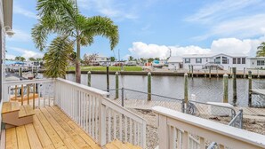 A waterfront property with a wooden deck, a view of the marina, and a clear sky.