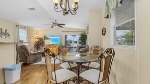 A dining area with a glass-top table, wicker chairs, and a ceiling fan.