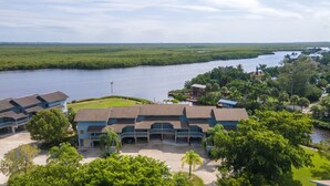 A hotel with multiple-story buildings, a waterfront view, and a surrounding lush landscape. - Blue Crab Key Condo with Amazing Water Views! (Saint James City)