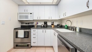 A modern kitchen with white cabinets, a stainless steel stove, a microwave, and a dishwasher. - Blue Crab Key Condo with Amazing Water Views! (Saint James City)