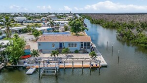 Une propriété située au bord de l’eau, dotée d’un quai, d’un bateau et d’une maison avec un toit bleu.