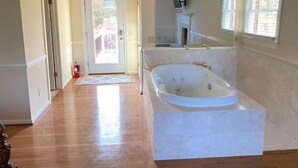 Ein geräumiges Badezimmer mit einer großen Badewanne, einer großzügigen Dusche und einer sichtbaren Toilette.
