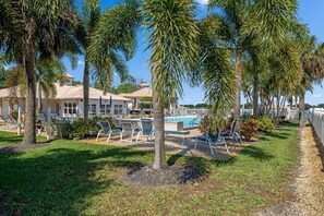 A pool area with lounge chairs and palm trees.