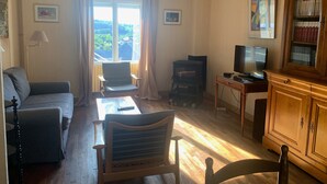 Ein Wohnzimmer mit einer Couch, Sesseln, einem Fernseher, einem Bücherregal und einem Kamin.