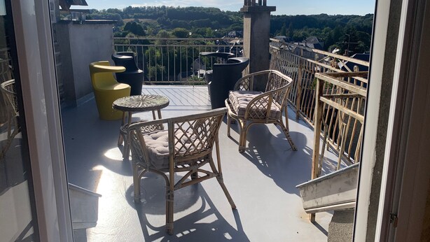Ein Balkon mit Korbmöbeln, Blick auf das Land und eine Steinstruktur.