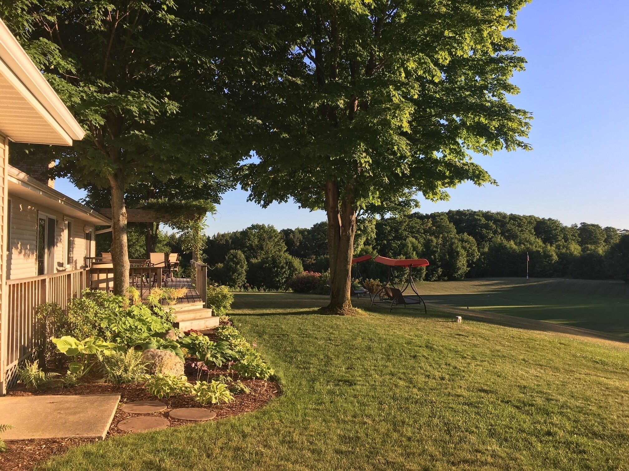 Une maison dotée d’un porche abrité, d’une pelouse et offrant une vue sur un terrain de golf.