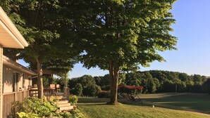 Ein Haus mit überdachter Veranda, Rasen und Blick auf einen Golfplatz.