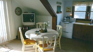 A dining area with a round table, four chairs, a television, and a kitchen area with a stove and sink. - Quiet Getaway Within Walking Distance of the Beach and Mall. (Cape May)