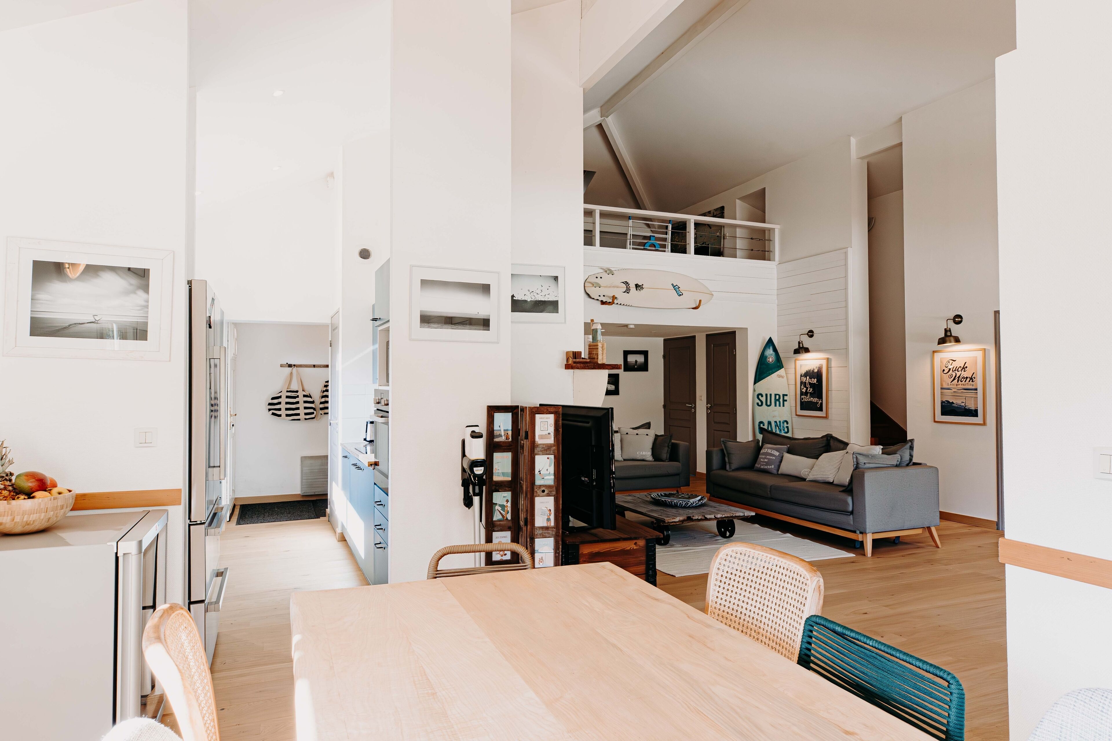 Ein geräumiger Wohnbereich mit Esstisch, Sofa und einer Erkergaube, inklusive Surfbrett.