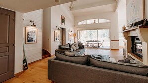 Ein großzügiges Wohnzimmer mit einer großen grauen Couch, einem Kamin und einem Essbereich mit Tisch und Stühlen.
