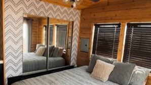 A bedroom with a large bed, wooden ceiling, and a ceiling fan. - Private Tiny Home with deck, fire pit & patio near Platte Creek Recreation area (Platte)