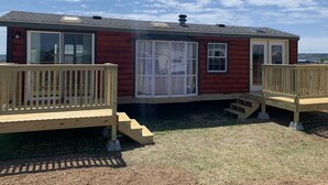 A small wooden cabin with a deck and a large window. - Private Tiny Home with deck, fire pit & patio near Platte Creek Recreation area (Platte)