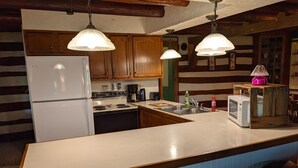 Una cocina con armarios de madera, un refrigerador blanco, una estufa y un microondas sobre una isla de madera.