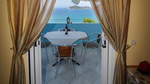 A room with a view of the sea, a table with chairs, and a bottle. - Agios Georgios - 2 Beds - Sleeps 5 - Free Parking (Corfu)