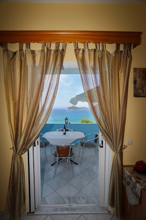 Enjoy the ocean view from this room's glass door, which leads to a space with a round table and chairs, a small table with refreshments, and a comfortable seating area.