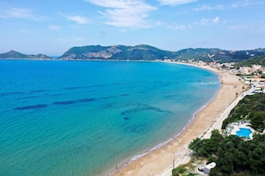 Une plage côtière aux eaux bleues et limpides, avec un rivage sablonneux et un espace piscine.