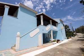 Stunning two-story residence with a central entrance, balcony, and potted plants.