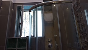 Uma casa de banho moderna com cabine de chuveiro em vidro, teto com iluminação embutida e um design de parede estampado.