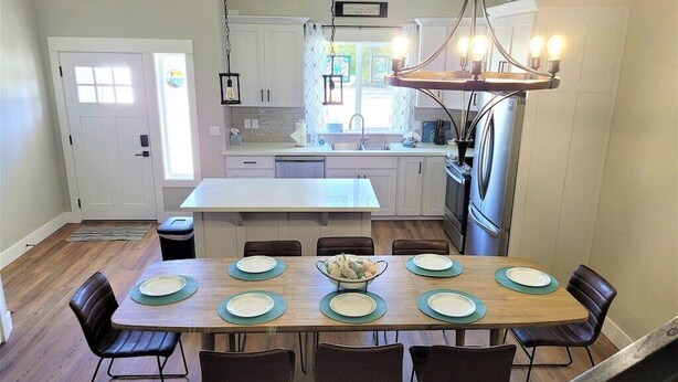 Een moderne keuken met een centraal eiland, witte kasten en een hangende lamp.