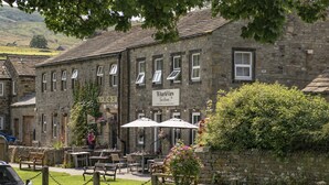 A stone building with a sign reading "Wharfview Tea Room" and outdoor seating with umbrellas. - 1 Riverside Cottage, Burnsall, Yorkshire Dales (Burnsall)