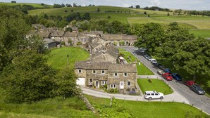 A rural village with stone houses, a main road, and parked cars. - 1 Riverside Cottage, Burnsall, Yorkshire Dales (Burnsall)