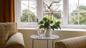 A room with a window, a small table with a plant and two glasses, and two sofas. - Fox Cottage, Middleham, Yorkshire Dales (Middleham)