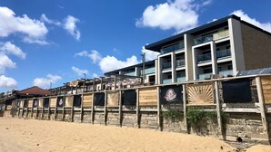 Ein Hotel direkt am Strand mit modernem Design, mit Balkonen und einem Sandstrand im Vordergrund.