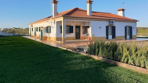 Ein zweistöckiges Haus mit Ziegeldach, Schornstein und einem gepflegten Rasen.