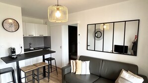 A modern living room with a sofa, coffee table, and a kitchen area in the background.