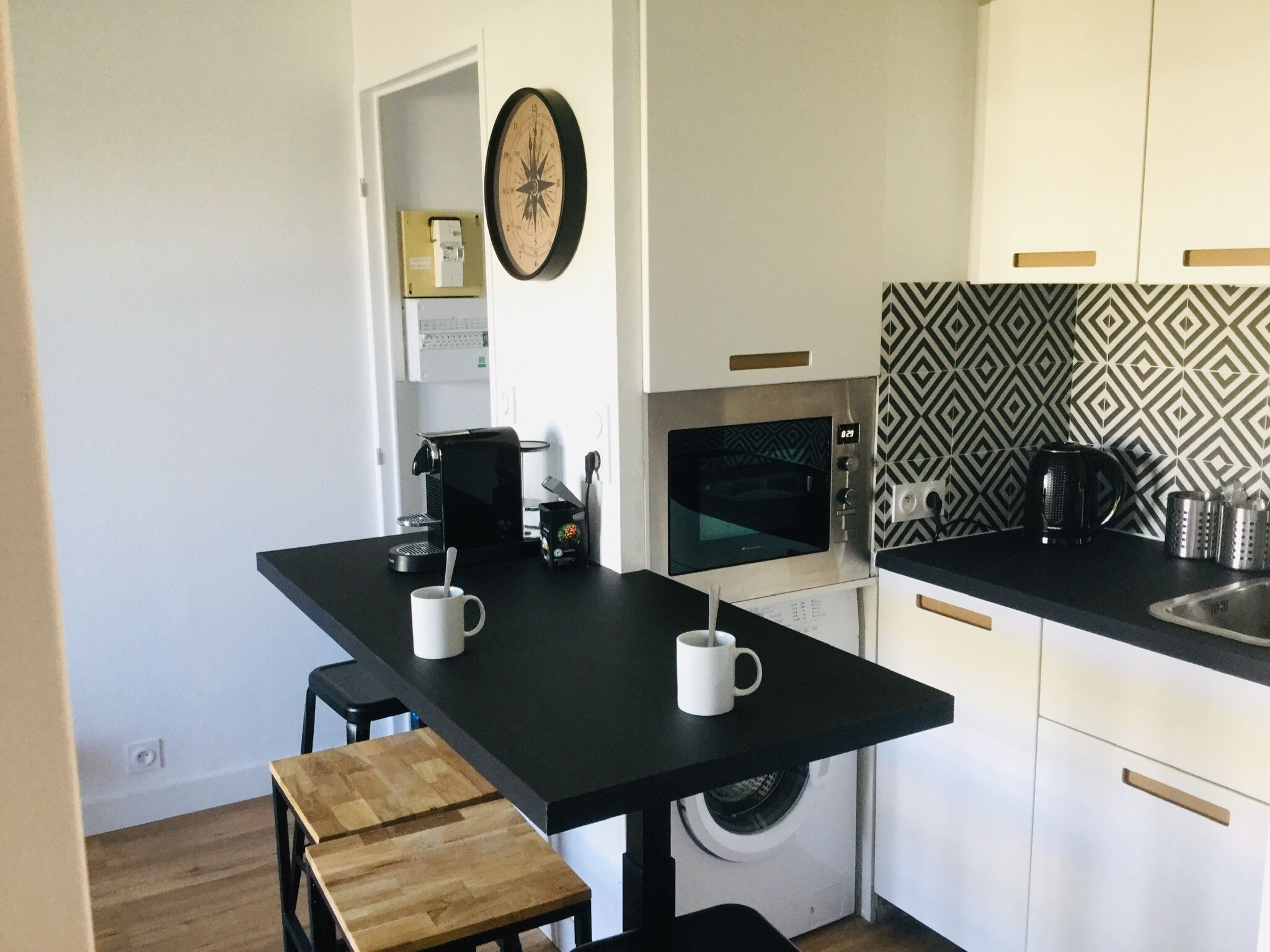 Een kleine keuken met een koffiezetapparaat, magnetron en wasmachine.