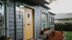 A house with a yellow door, a mailbox, and a small porch area with a welcome mat. - Modern House, Walk To Historic Downtown! (Grants Pass)