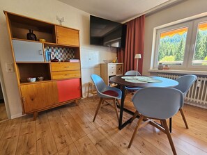 Un espace de vie compact comprenant un coin repas, un téléviseur, une fenêtre avec vue et une kitchenette.