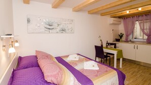 A bedroom with a bed, a desk, and a window with curtains. - Lavender Garden Apartments - Comfort Studio Apartment (Ground Floor) (Dubrovnik)