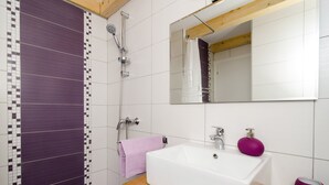 Ein Badezimmer mit einem weißen Waschbecken, violetten Fliesen, einem Holzregal und einem Spiegel über dem Waschbecken.