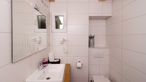 Ein modernes Badezimmer mit großem Spiegel, Waschbecken, Toilette und Duschbereich.