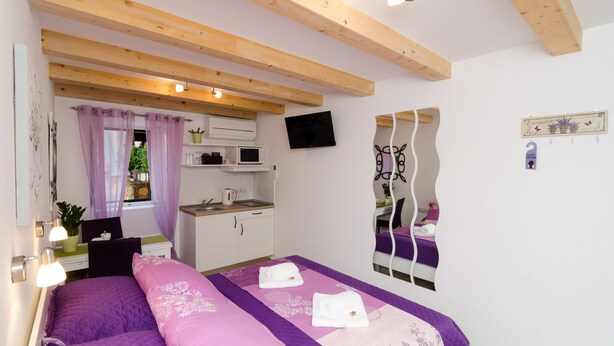 Ein Schlafzimmer mit Bett, Schreibtisch, Spiegel und einem Fenster mit Vorhängen.