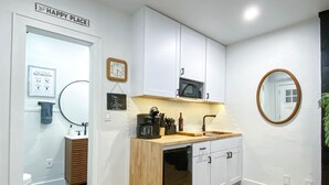 A modern kitchen with white cabinets, a wooden countertop, a microwave, and a sink. - Modern Studio in the Heart of Grants Pass (Grants Pass)