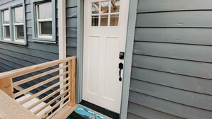 A house with a white front door, a small porch with a wooden railing, and a welcome mat. - Modern Studio in the Heart of Grants Pass (Grants Pass)